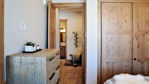 A hallway with a wooden dresser, a plant, and a door leading to another room. - BRAND NEW Contemporary 2 BR near Winter Park Ski Resort on Shuttle w/priv hottub (fraser)