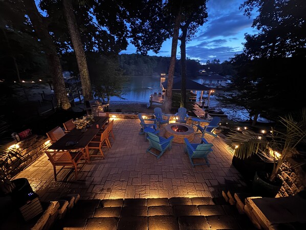 An outdoor patio with a fire pit, seating, and a view of a body of water.