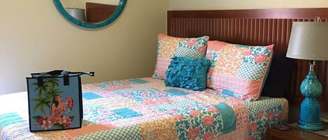 A bedroom with a bed, a nightstand, a lamp, a mirror, and an air conditioner.