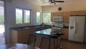 A modern kitchen with a central island, stainless steel appliances, and large windows offering views of the outdoors. - Southern Utah getaway  (Apple Valley)