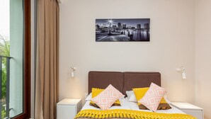 A modern hotel room with a large bed, a cityscape view, and a balcony.