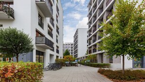 A modern apartment building with balconies, a paved courtyard, and bicycles.