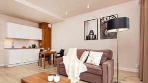 A modern living room with a sofa, coffee table, and a dining area with a table and chairs.
