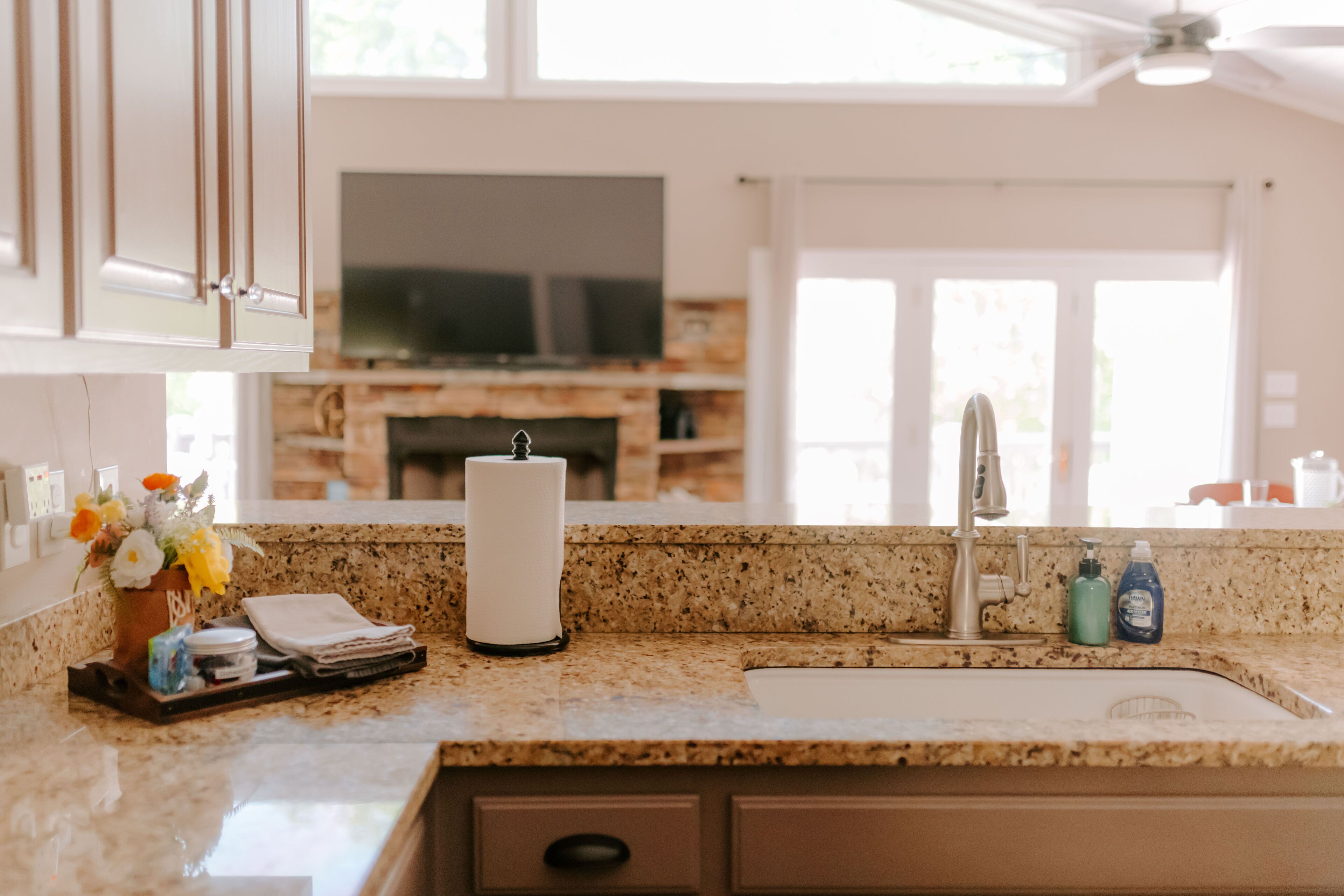 Una cocina con encimeras de granito, estufa integrada y televisor de pantalla plana sobre la estufa.