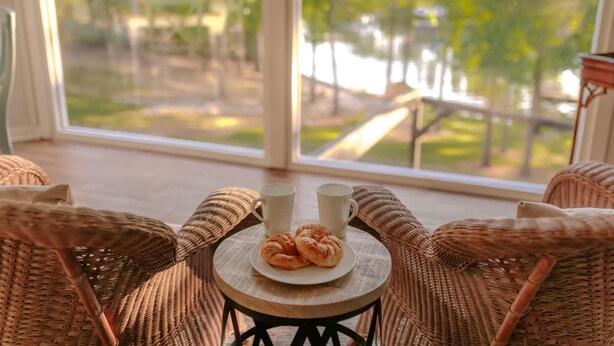 A wicker chair with a small table, two white mugs, and a plate with croissants. - THANKSGIVING on Lake Keowee! Sleeps 18, Dock, Fire Pits, Kayaks, Pet Friendly (Seneca)