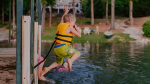 A child in a yellow life jacket jumping off a dock into a body of water. - THANKSGIVING on Lake Keowee! Sleeps 18, Dock, Fire Pits, Kayaks, Pet Friendly (Seneca)