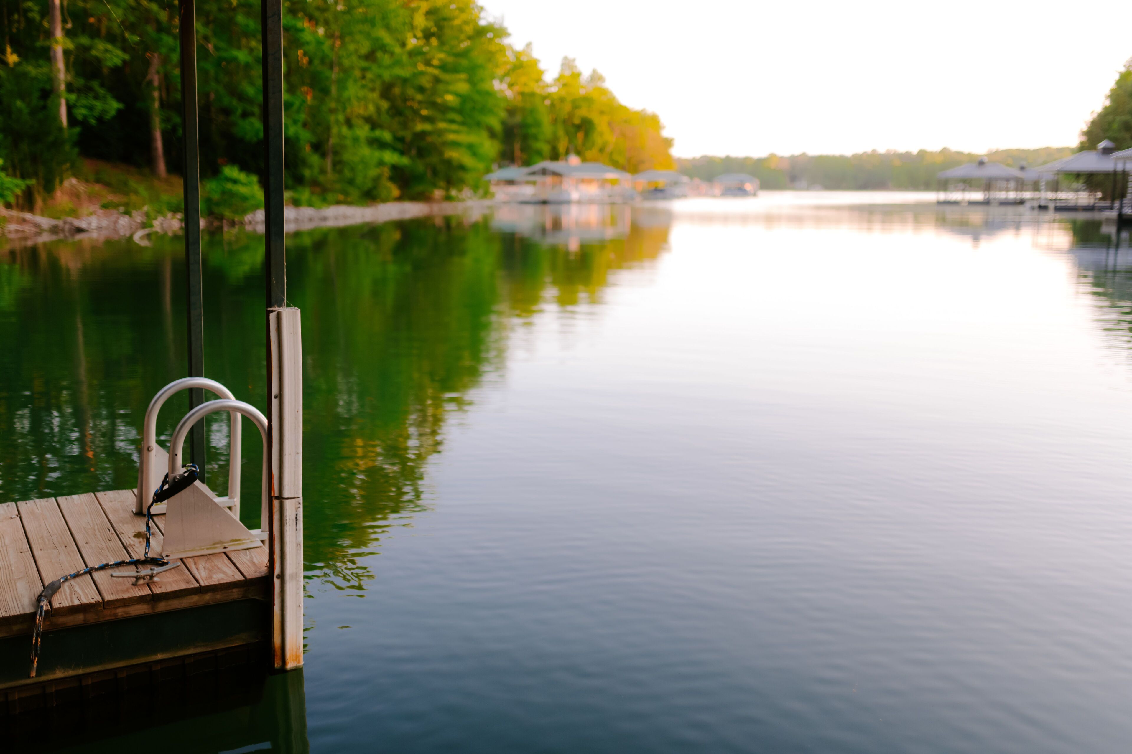 Un lac paisible, avec une jetée en bois et un bateau amarré à son extrémité.