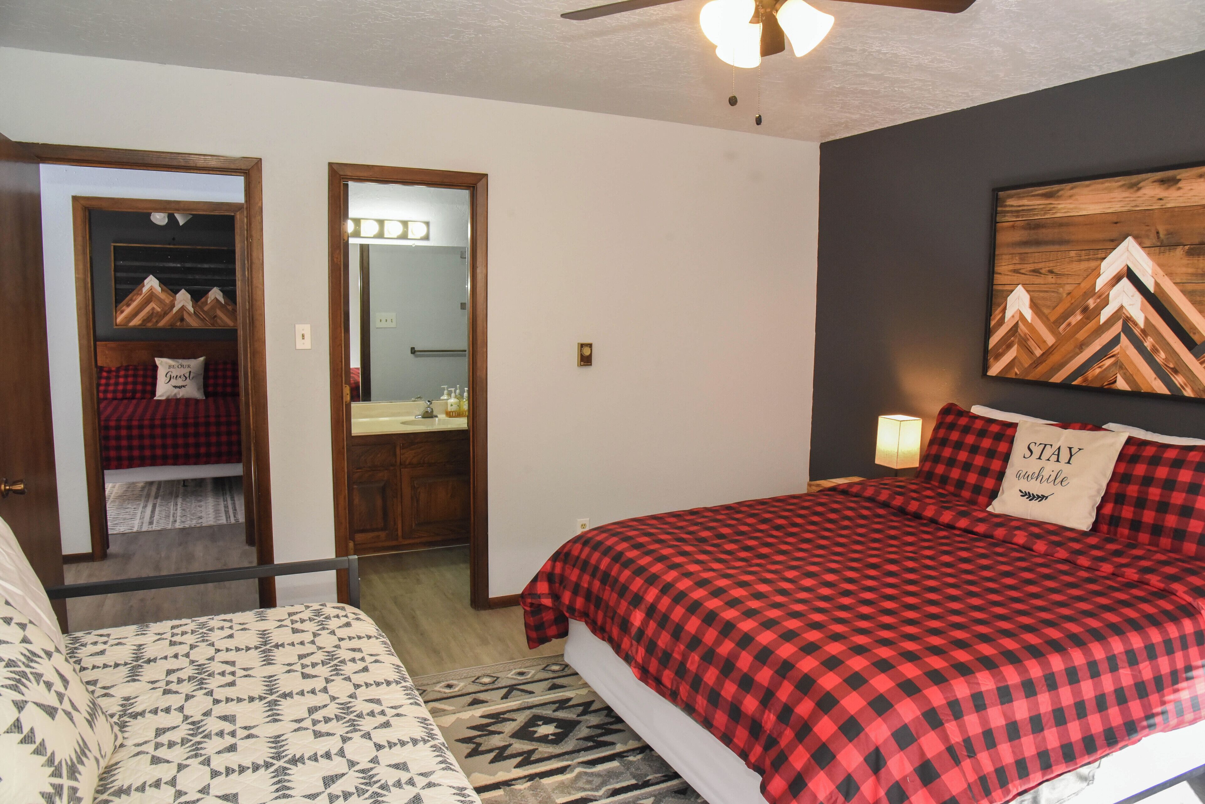 A bedroom with a bed, a nightstand, a mirror, and a door leading to a bathroom.