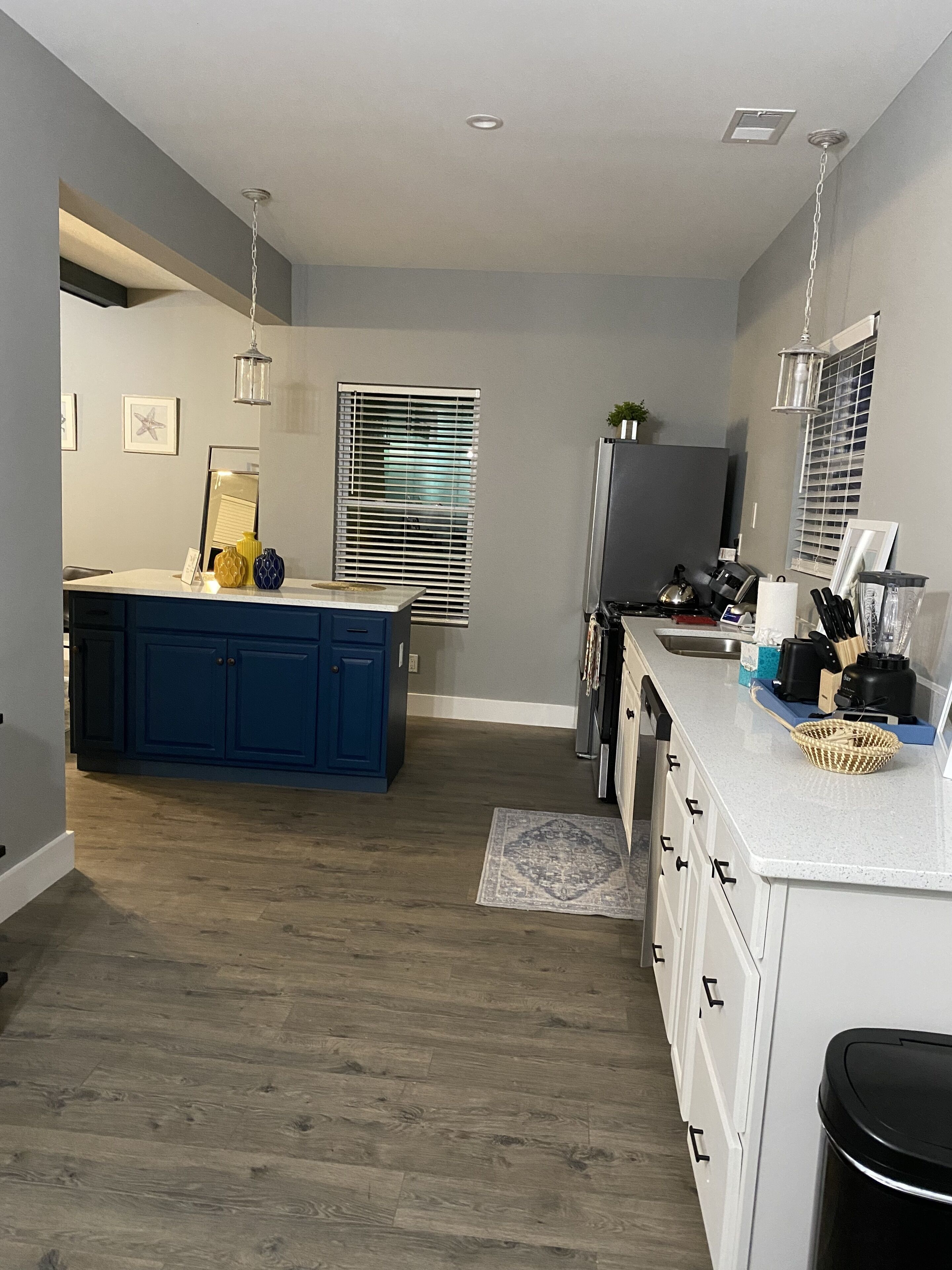 Une cuisine moderne dotée d’un îlot central, de meubles blancs et d’un plancher en bois.