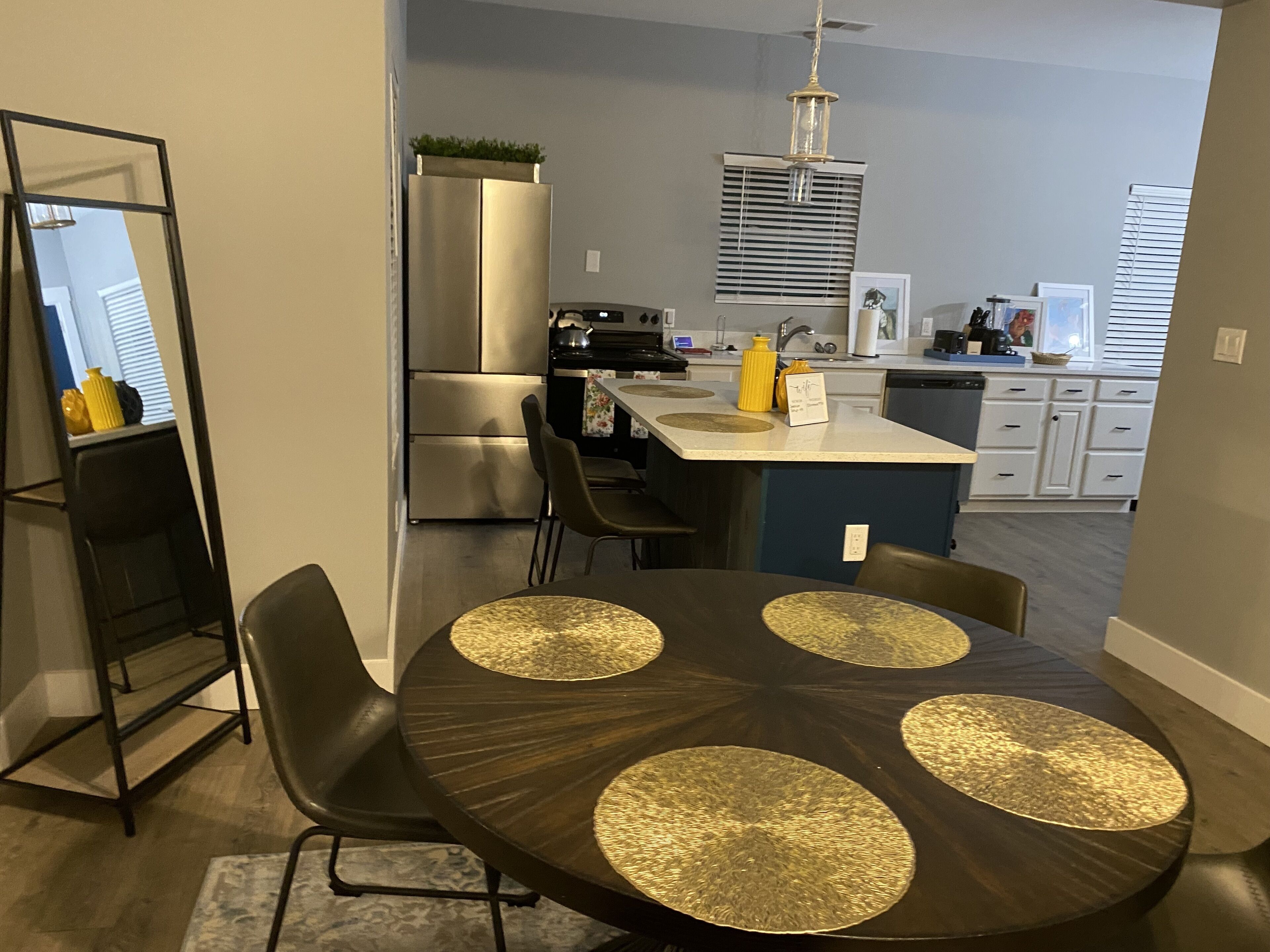 Una cocina moderna con una isla central, electrodomésticos de acero inoxidable y un comedor con una mesa redonda y sillas.