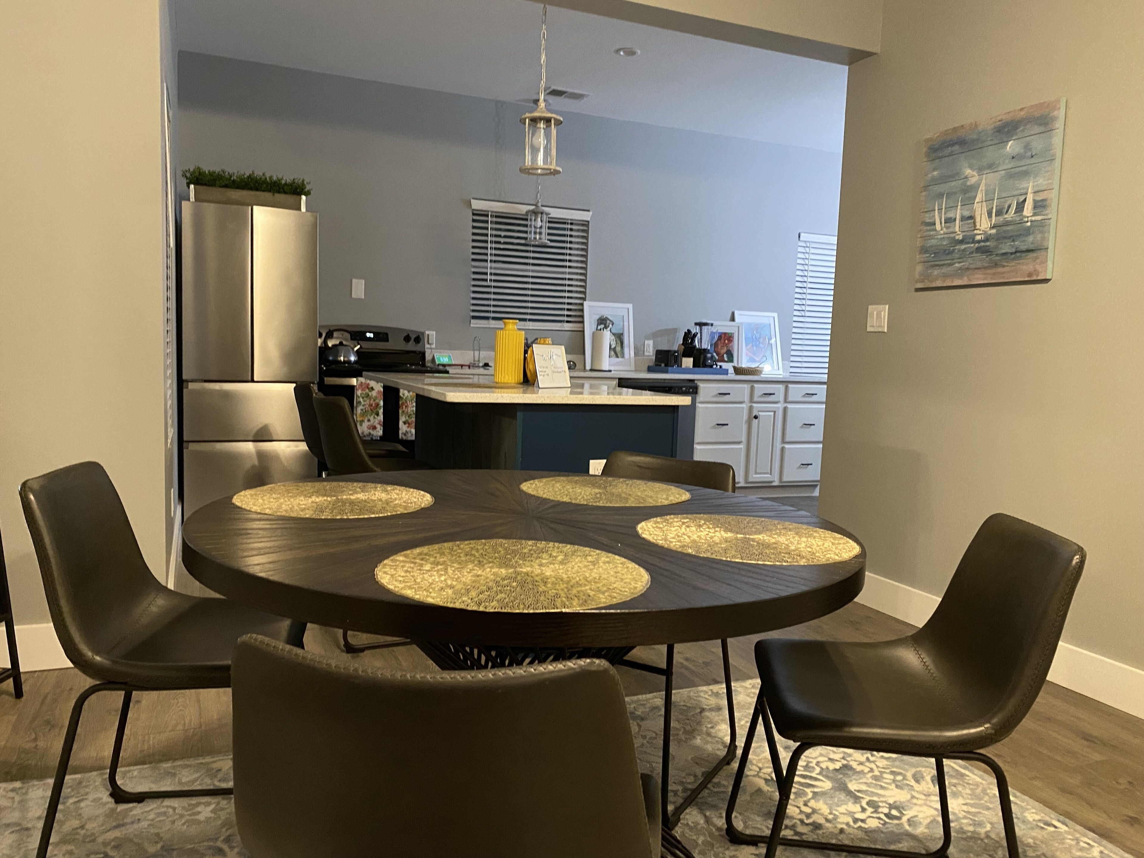 Un coin repas avec une table ronde, quatre chaises et une cuisine en arrière-plan.