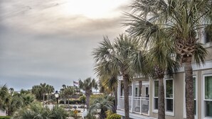 A residential building with a balcony, surrounded by palm trees and other greenery. - First Floor Ocean View! Pet Friendly! Sleeps 6! Amenity access included! (Seabrook Island)