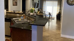 Una cocina moderna con una isla central, iluminación colgante y una zona de comedor al fondo.