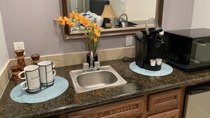 Una cocina con encimera de granito, cafetera, microondas y lavabo.