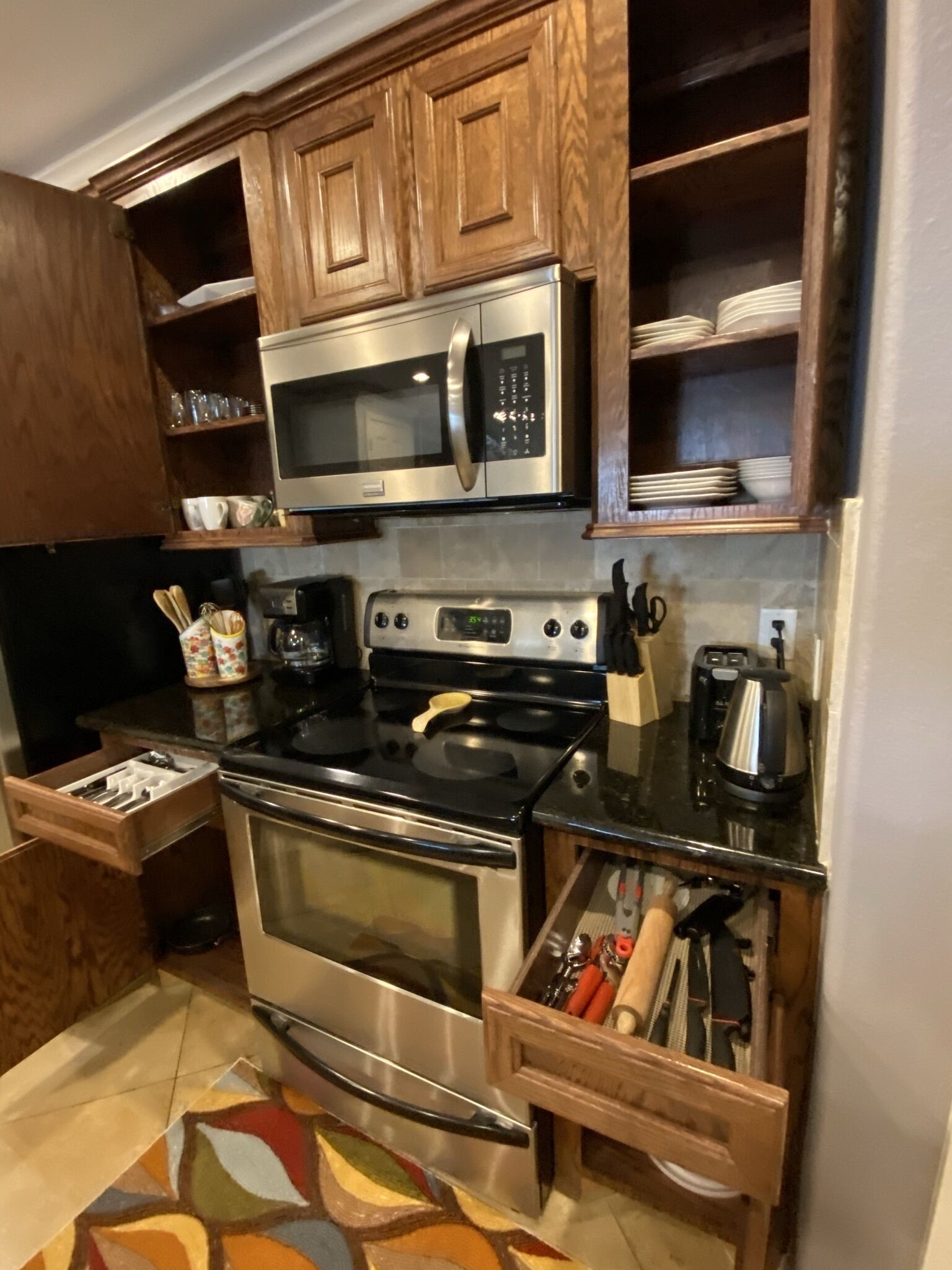 A kitchen with wooden cabinets, a stainless steel microwave, a stove, and a coffee maker.