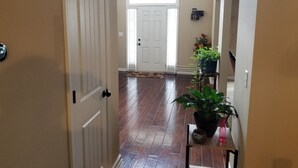 Un pasillo con suelo de madera, puertas blancas y una planta en maceta sobre una pequeña mesa.