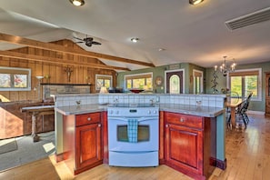 Enjoy cooking in this kitchen with a central island, oven, and stovetop, surrounded by a vaulted ceiling and large window.