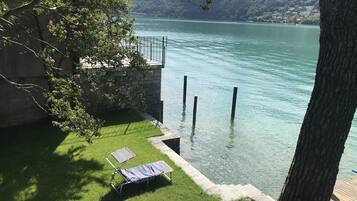 Une vue sur le lac, avec une pelouse, un fauteuil de relaxation et un mur en pierre.