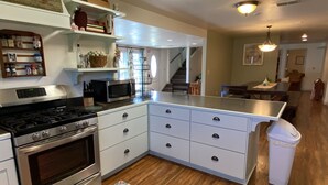 A modern kitchen with a stainless steel stove, white cabinets, and a microwave.