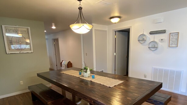 A spacious dining area with a large wooden table, benches, and a hanging light fixture.