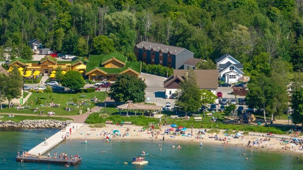 Un resort sul lago con un molo, spiaggia e diversi edifici, tra cui un lodge e un ristorante.