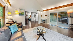 A modern living room with a fireplace, a glass coffee table, and a sofa with patterned cushions.