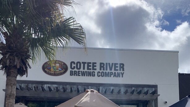 Ein Gebäude der COTEE RIVER BREWING COMPANY mit Außenbereich und Sonnenschirmen.