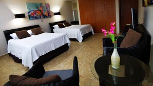 A hotel room with two beds, a sofa, a coffee table, and a TV. - Cozy Studio In Beachfront Condominium (Cancun)