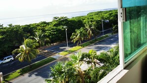 A view from a window overlooking a street lined with palm trees and a road leading to the ocean. - Cozy Studio In Beachfront Condominium (Cancun)