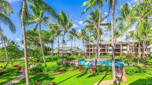 Un resort con piscina, palmeras y un jardín bien cuidado.