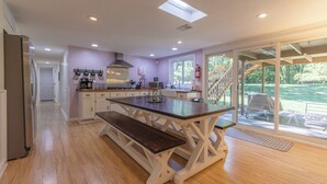 A modern kitchen with a central island, wooden flooring, and a sliding glass door leading to an outdoor area. - Plum Creek - Large home with 2 kitchens close to Pier Cove! (Fennville)