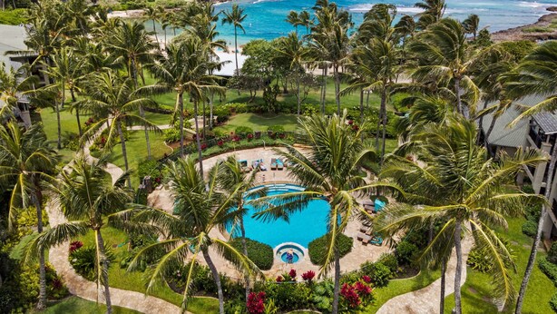 A resort with a central swimming pool, surrounded by palm trees and a view of the ocean. - Turtle Bay Villas 307 by Gather: Beachfront w/ Shared Pool/Spa/AC (Kahuku)
