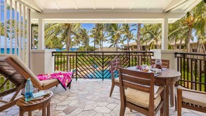 A covered outdoor area with a pool, lounge chairs, and a dining table. - Turtle Bay Villas 308 by Gather: Beachfront w/ Shared Pool/Spa/AC (Kahuku)