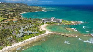 An aerial view of a resort with a large building, beachfront, and clear waters. - Turtle Bay Villas 310 by Gather: Beachfront w/ Shared Pool/Spa/AC (Kahuku)