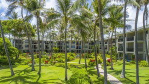 A hotel with multiple floors, surrounded by lush greenery and palm trees. - Turtle Bay Villas 310 by Gather: Beachfront w/ Shared Pool/Spa/AC (Kahuku)