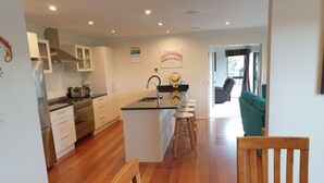 Una cocina moderna con armarios blancos, una isla central y un comedor con sillas y una mesa de madera.