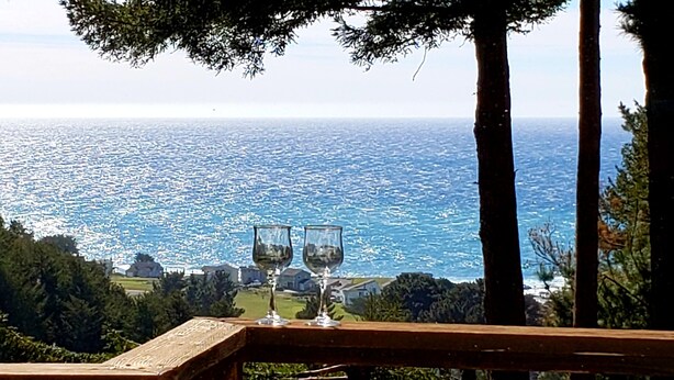 A wooden deck with two empty wine glasses overlooking a coastal view. - Wow! Amazing Oceanview, walk to Beach & Game room! (Whitethorn)