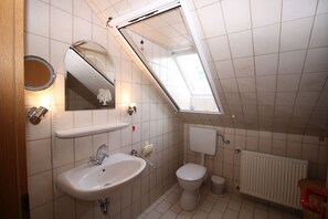 Ein Badezimmer mit Oberlicht, Waschbecken, Toilette und Handtuchheizkörper.