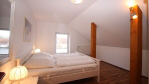 Ein Schlafzimmer mit einem Bett, einem Nachttisch, einer Lampe, einem Fenster und einer Heizung.