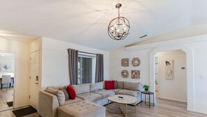 Una sala moderna con un sofá modular, una mesa de centro redonda y una araña.