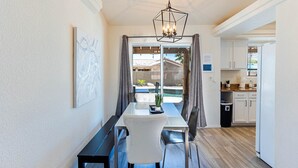 Un comedor con mesa y sillas, una lámpara colgante y vistas al exterior.