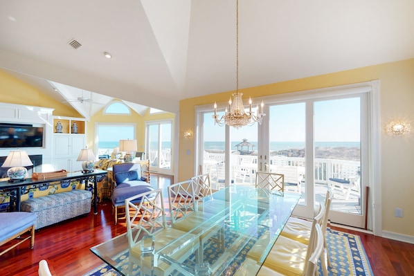 Relax in this stylish living area with a large dining table, comfortable seating, and a high ceiling.