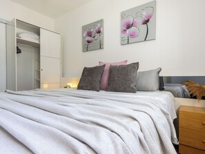 A bedroom with a bed, pillows, a nightstand, a dresser, and two wall art pieces. - Estrella by Interhome (Deltebre)