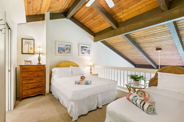 Camera da letto con soffitto in legno, un letto con biancheria bianca, un comò in legno e due lampade a parete.