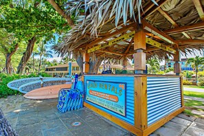 Un petit kiosque de location situé sur la plage, avec une enseigne publicitaire pour la location de planches de stand-up paddle et de kayaks.