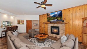 A living room with a sectional sofa, a fireplace, a television, and a dining area with chairs.