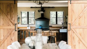 A rustic kitchen with wooden cabinets, a stove, and a large window.