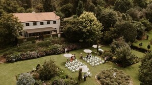 A garden wedding venue with a white building, arranged seating, and umbrellas.