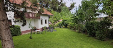 Een huis met een rode dakbedekking, een witte gevel en een verzorgd gazon.