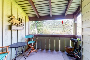 Relax on the covered porch with a wooden bench and folding chair, perfect for unwinding or casual gatherings.